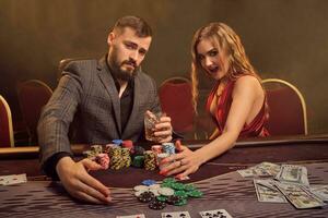 Charming wealthy couple are playing poker at a casino. photo