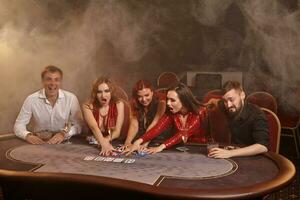 Group of a young wealthy friends are playing poker at a casino. photo