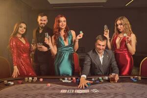 Group of a young wealthy friends are playing poker at a casino. photo