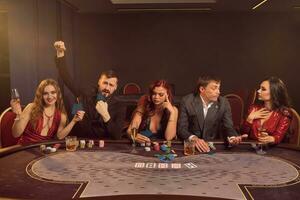 Group of a young wealthy friends are playing poker at a casino. photo