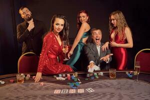 Group of a young wealthy friends are playing poker at a casino. photo