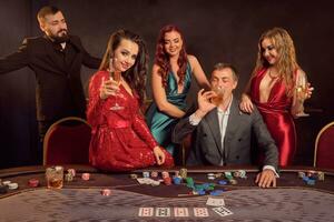 Group of a young wealthy friends are playing poker at a casino. photo