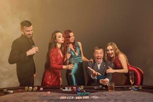 Group of a young wealthy friends are playing poker at a casino. photo