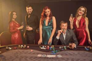 Group of a young wealthy friends are playing poker at a casino. photo