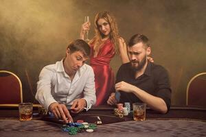 Group of a young wealthy friends are playing poker at a casino. photo