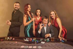 Group of a young wealthy friends are playing poker at a casino. photo