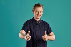 Close-up portrait of a ginger guy in navy t-shirt posing on blue background. Sincere emotions. photo