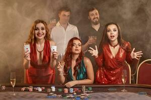 Group of a young wealthy friends are playing poker at a casino. photo