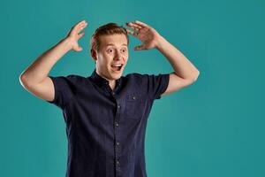 Close-up portrait of a ginger guy in navy t-shirt posing on blue background. Sincere emotions. photo