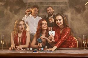 Group of a young wealthy friends are playing poker at a casino. photo