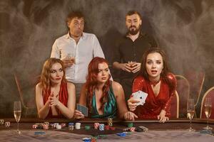 Group of a young wealthy friends are playing poker at a casino. photo