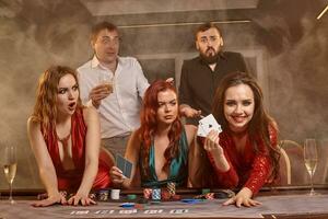 Group of a young wealthy friends are playing poker at a casino. photo