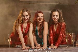 Three beautiful young women are playing poker at a casino. photo