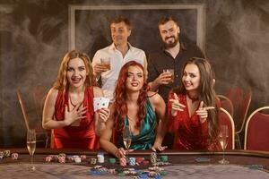 Group of a young wealthy friends are playing poker at a casino. photo