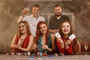 Group of a young wealthy friends are playing poker at a casino. photo