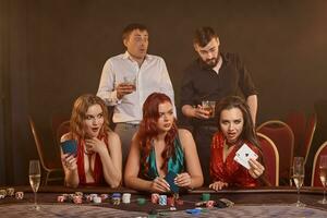 Group of a young wealthy friends are playing poker at a casino. photo