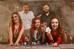 Group of a young wealthy friends are playing poker at a casino. photo