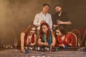 Group of a young wealthy friends are playing poker at a casino. photo