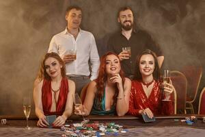 Group of a young wealthy friends are playing poker at a casino. photo