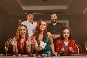 Group of a young wealthy friends are playing poker at a casino. photo