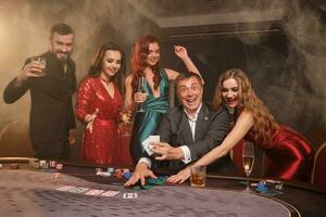 Group of a young wealthy friends are playing poker at a casino. photo