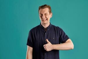 Close-up portrait of a ginger guy in navy t-shirt posing on blue background. Sincere emotions. photo