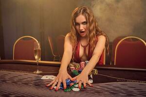 Charming woman with a beautiful hairstyle and perfect make-up is playing poker. Casino. photo