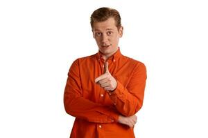 Close-up portrait of a ginger guy in orange shirt posing isolated on white background. Sincere emotions. photo