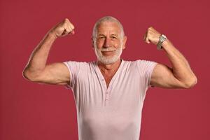 Handsome mature man posing against a pink studio background. photo