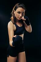 Athletic woman in boxing mittens is practicing karate in studio. photo
