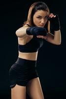 Athletic woman in boxing mittens is practicing karate in studio. photo