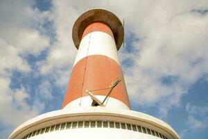 a white and red lighthouse with a blue sky background photo