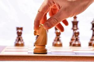 un persona es colocación un pedazo en un ajedrez tablero foto