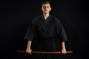 kendo gurú vistiendo en un tradicional japonés kimono es practicando marcial Arte con el shinai bambú espada en contra un negro estudio antecedentes. foto