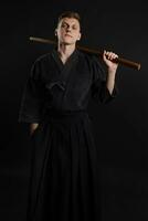 kendo gurú vistiendo en un tradicional japonés kimono es practicando marcial Arte con el shinai bambú espada en contra un negro estudio antecedentes. foto