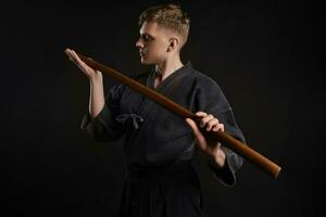 kendo gurú vistiendo en un tradicional japonés kimono es practicando marcial Arte con el shinai bambú espada en contra un negro estudio antecedentes. foto