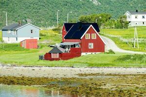 a red house on the shore of a body of water photo