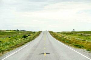 an empty road in the middle of a field photo