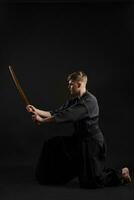 kendo gurú vistiendo en un tradicional japonés kimono es practicando marcial Arte con el shinai bambú espada en contra un negro estudio antecedentes. foto