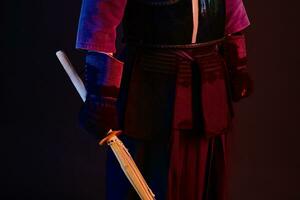 Close up shot, Kendo fighter wearing in an armor, traditional kimono is practicing martial art with shinai bamboo sword, black background. photo
