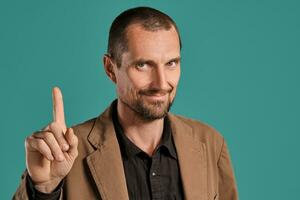 Middle-aged man with beard and mustache, wears black shirt and brown jacket posing against a blue background. Sincere emotions concept. photo