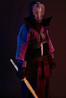 Close up shot, Kendo fighter wearing in an armor, traditional kimono, helmet practicing martial art with shinai bamboo sword, black background. photo