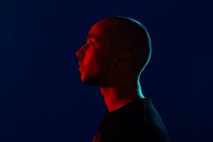 Studio shot of a young tattoed bald man posing against a blue background. 90s style. photo