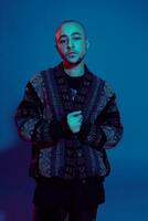 Studio shot of a young tattoed bald man posing against a colorful background. 90s style. photo