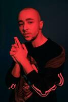 Studio shot of a young tattoed bald man posing against a dark blue background. 90s style. photo