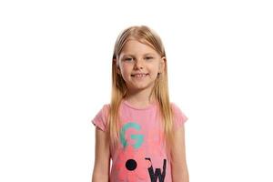 Close-up portrait of a nice blonde little kid in a pink t-shirt posing isolated on white background. photo