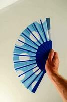 a person holding a blue and white polka dot fan photo