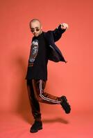 Studio shot of a young tattoed bald man posing against a pink background. 90s style. photo