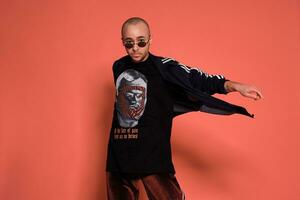 Studio shot of a young tattoed bald man posing against a pink background. 90s style. photo