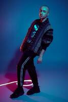 Studio shot of a young tattoed bald man posing against a colorful background. 90s style. photo